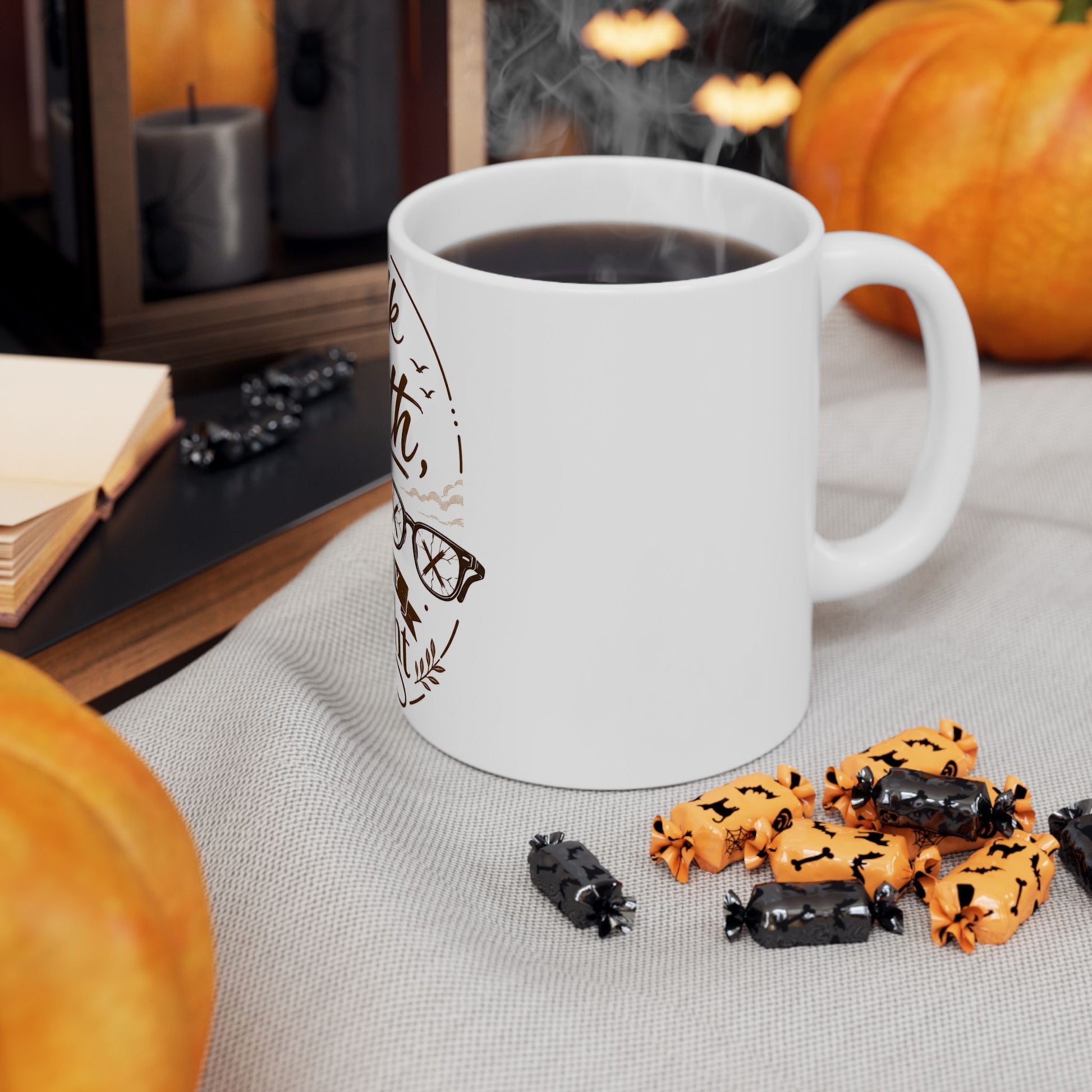 White mug with Halloween-themed text on a table with pumpkins and treats.