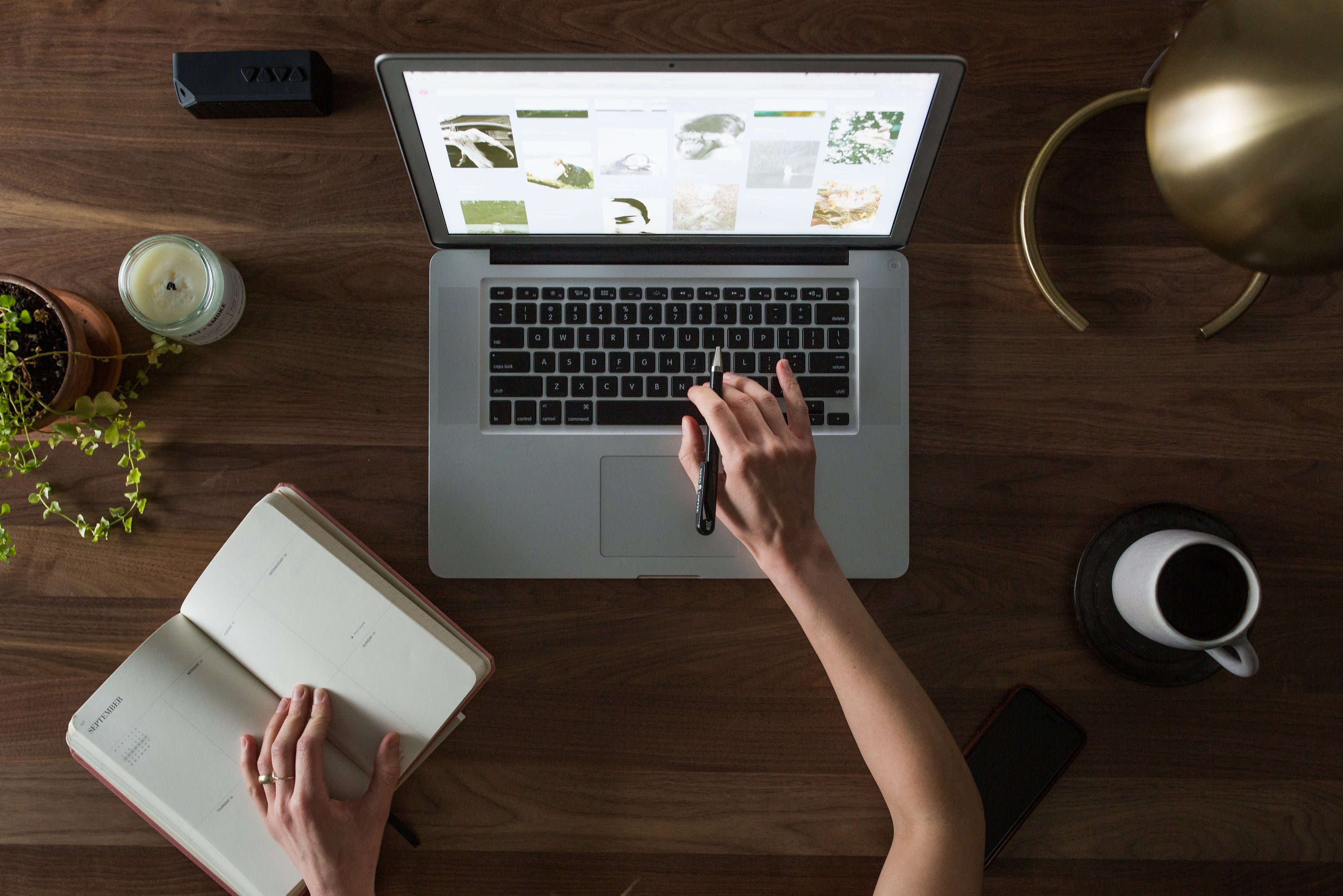 Person exploring inspirational and funny coffee mug designs online using desktop computer with coffee mug and book nearby